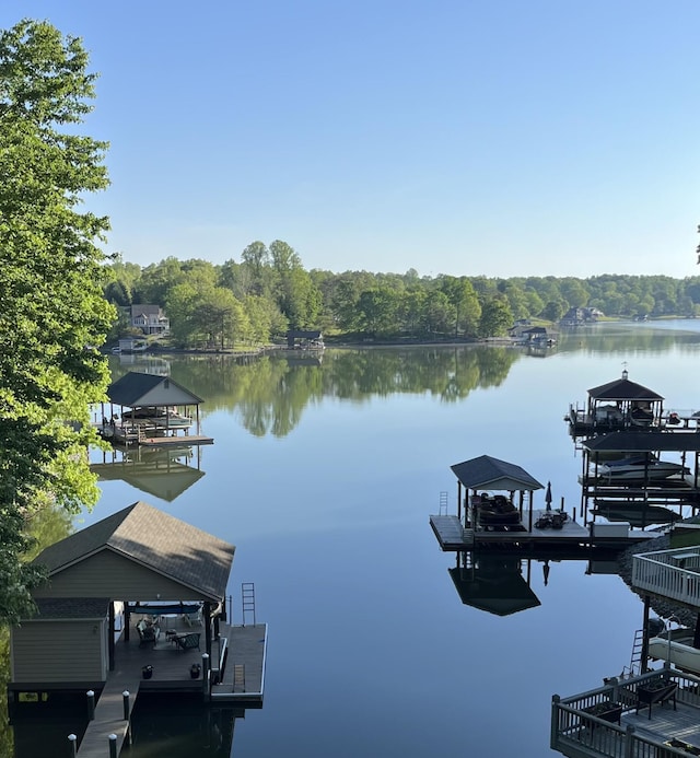 dock with boat lift, a water view, and a forest view