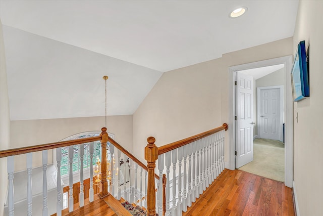 corridor with wood finished floors, an upstairs landing, recessed lighting, vaulted ceiling, and baseboards