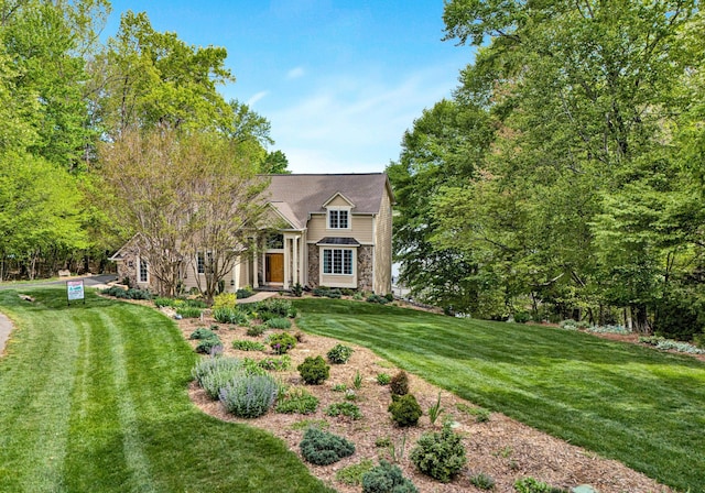shingle-style home featuring stone siding and a front yard