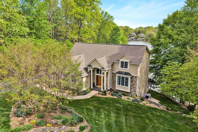 view of front of property with stone siding, cooling unit, and a front lawn