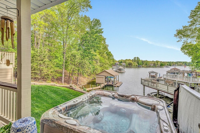 deck featuring a hot tub, a water view, a yard, and a dock