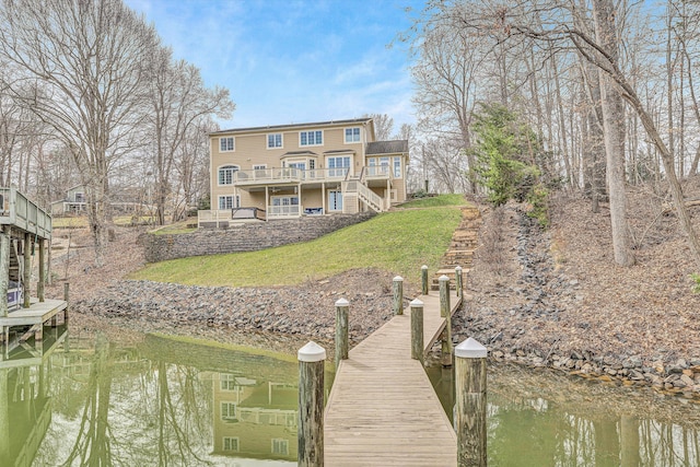 dock area with stairs, a yard, and a deck with water view