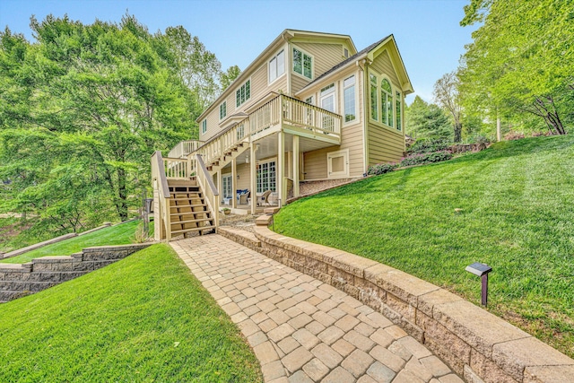 back of property featuring stairs, a wooden deck, a yard, and a patio area