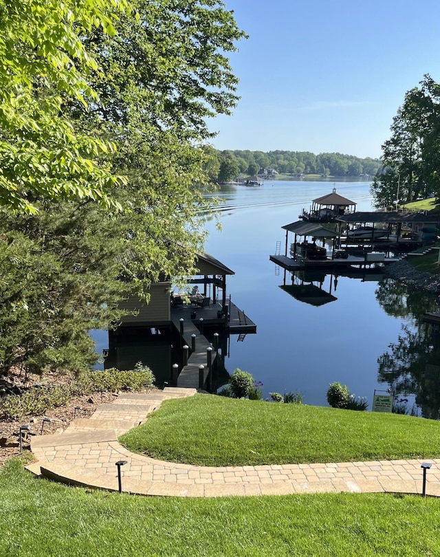 dock featuring a water view, a lawn, and boat lift