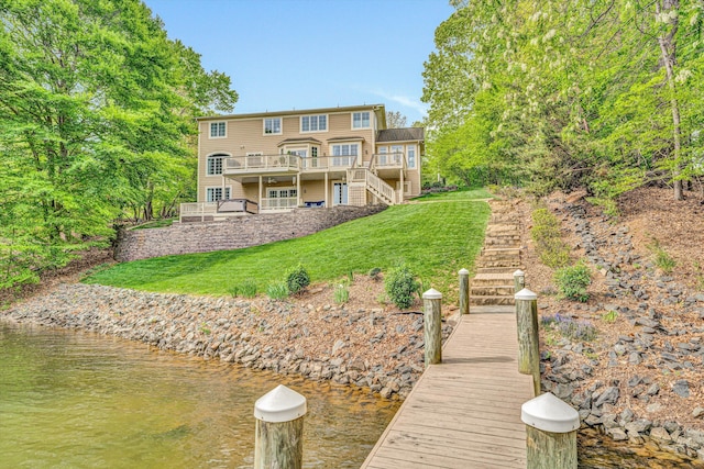 rear view of property with stairs, a lawn, and a deck with water view