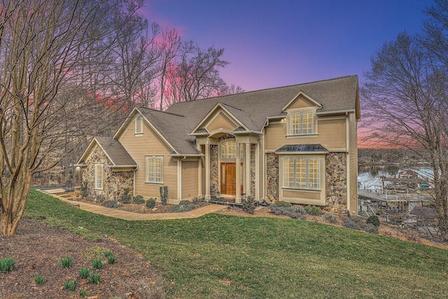 traditional-style house with a front lawn and stone siding