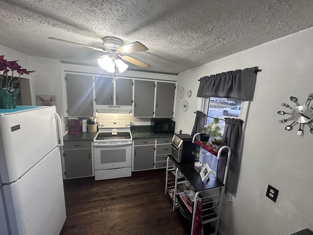 kitchen with dark wood-type flooring, under cabinet range hood, dark countertops, a textured ceiling, and white appliances