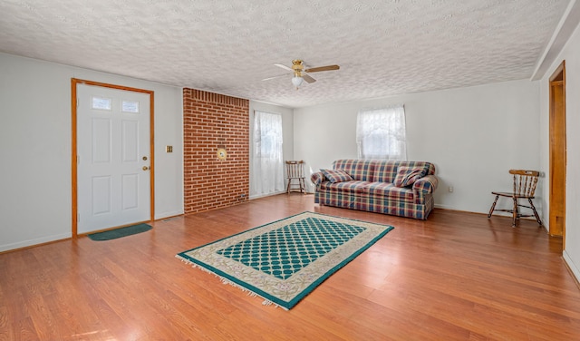 living area featuring wood finished floors, baseboards, and a textured ceiling