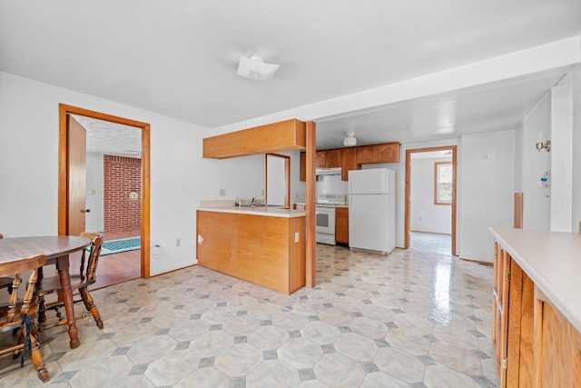 kitchen featuring under cabinet range hood, light countertops, brown cabinetry, white appliances, and a sink