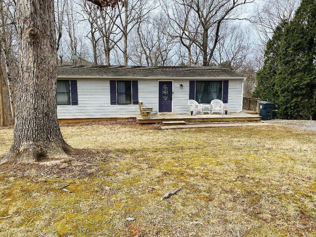 ranch-style house with a wooden deck and a front yard