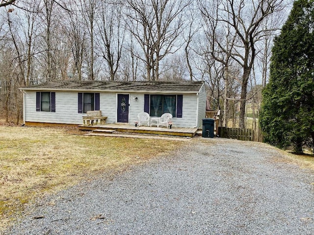 view of front of property with driveway, a wooden deck, and fence