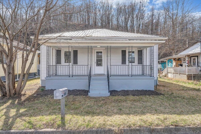 bungalow featuring a front yard, covered porch, and metal roof