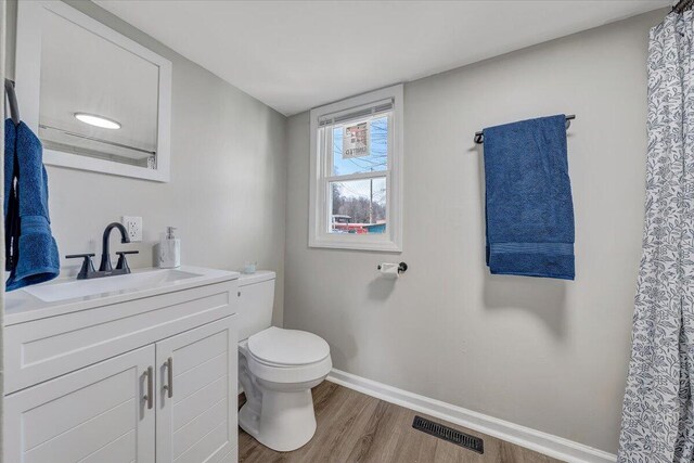 bathroom with visible vents, baseboards, toilet, wood finished floors, and vanity