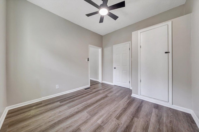 unfurnished bedroom with wood finished floors, baseboards, and ceiling fan