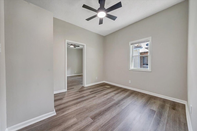 empty room featuring wood finished floors, baseboards, and a textured ceiling