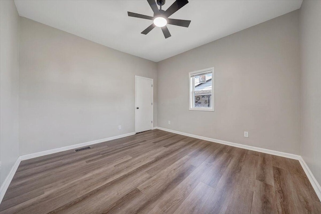 spare room with a ceiling fan, wood finished floors, visible vents, and baseboards