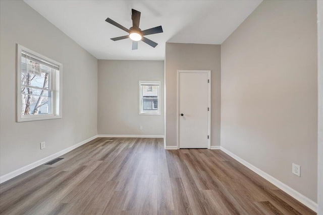 unfurnished room with visible vents, a healthy amount of sunlight, baseboards, and wood finished floors