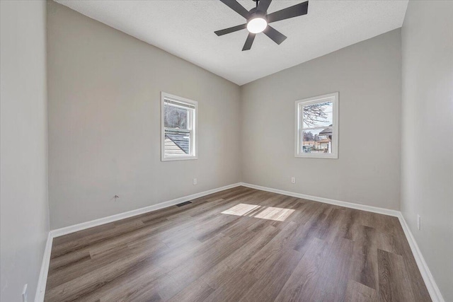 unfurnished room with wood finished floors, visible vents, and baseboards