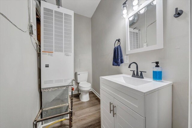 bathroom with baseboards, toilet, wood finished floors, and vanity