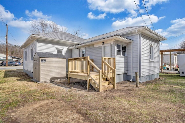 back of property featuring a storage unit, a lawn, a wooden deck, an outdoor structure, and metal roof