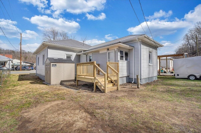 rear view of property featuring an outdoor structure, a deck, a storage shed, a lawn, and metal roof