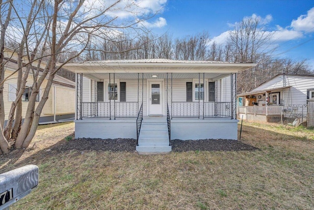 bungalow featuring covered porch, metal roof, and a front yard