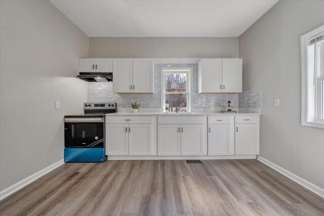 kitchen featuring under cabinet range hood, baseboards, white cabinetry, and electric stove