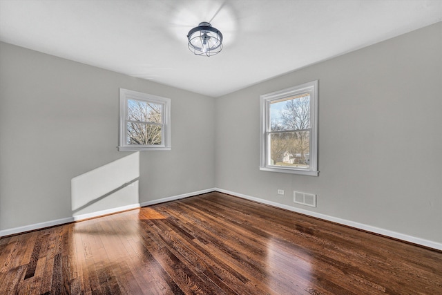 unfurnished room featuring visible vents, baseboards, and hardwood / wood-style floors