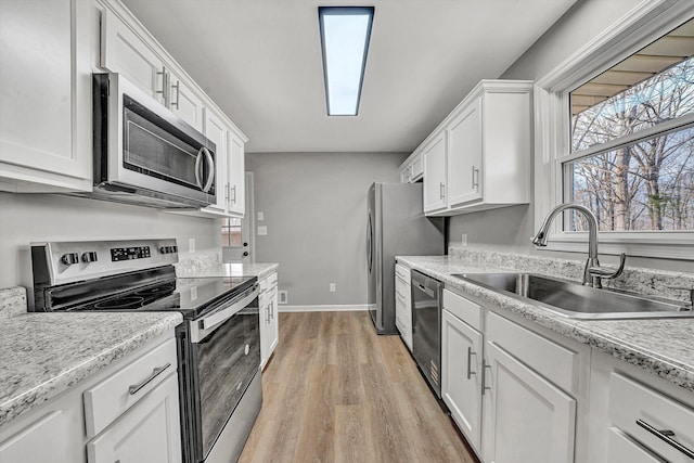 kitchen with a sink, light wood-type flooring, white cabinetry, and stainless steel appliances