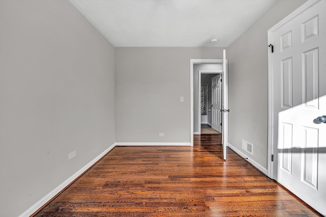 spare room featuring wood finished floors, visible vents, and baseboards