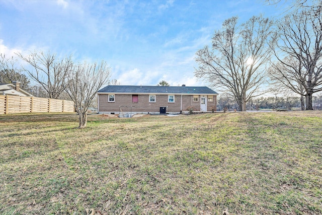 back of house featuring brick siding, a yard, and fence