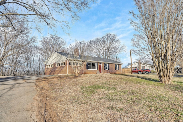 ranch-style house with brick siding, a chimney, a front lawn, and fence