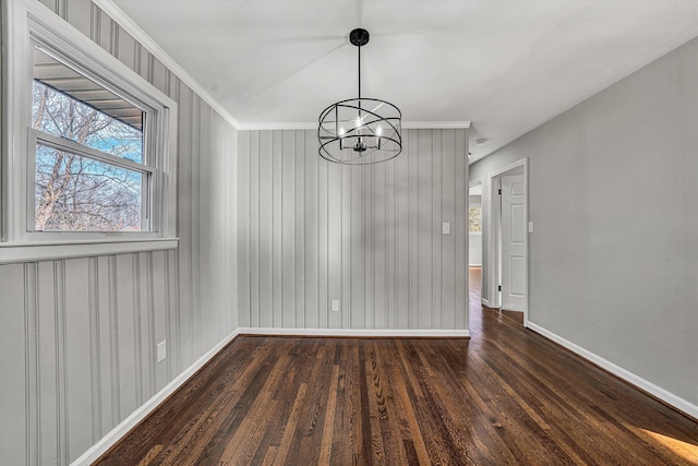 unfurnished dining area with baseboards, an inviting chandelier, wood finished floors, and crown molding