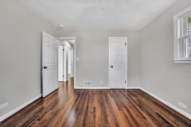 unfurnished bedroom featuring dark wood-style floors, visible vents, and baseboards