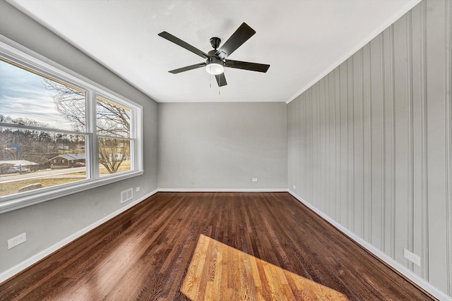 empty room with visible vents, baseboards, dark wood-type flooring, and a ceiling fan