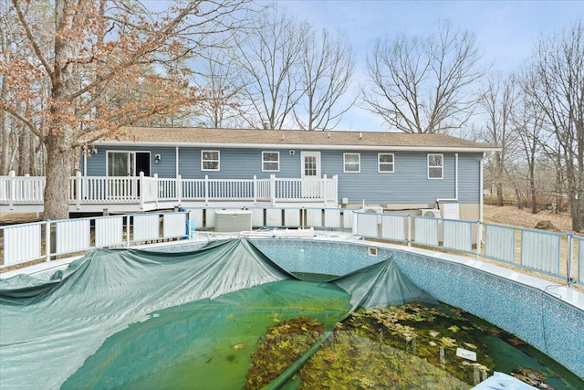 view of swimming pool featuring a covered pool, fence, and a wooden deck