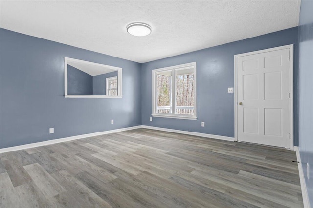 spare room with a textured ceiling, baseboards, and wood finished floors