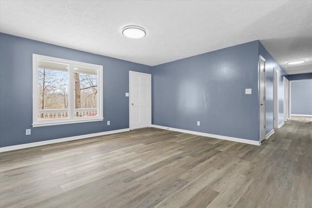 unfurnished room with baseboards, a textured ceiling, and wood finished floors