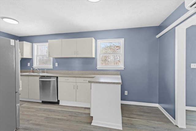 kitchen with a sink, light wood-style floors, dishwasher, and freestanding refrigerator