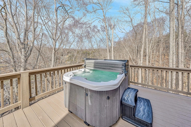 deck with a wooded view and a hot tub