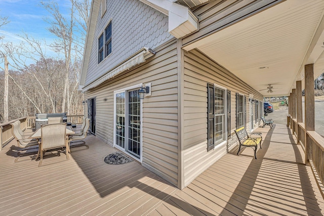 wooden deck with outdoor dining area and ceiling fan