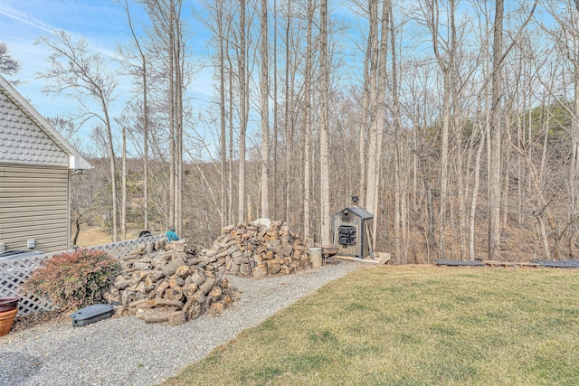 view of yard featuring a forest view, a storage shed, and an outdoor structure