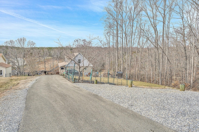 view of street with driveway and a view of trees