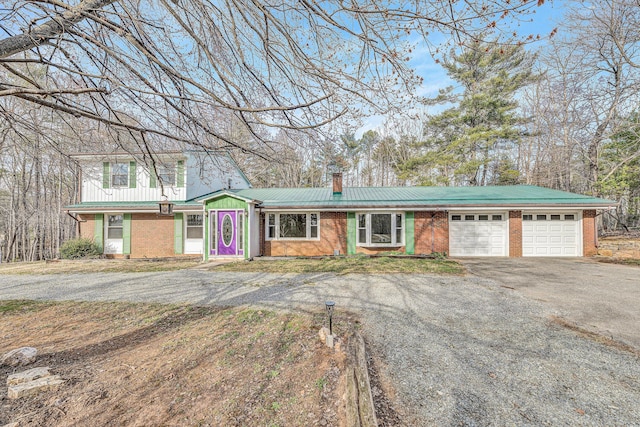 view of front of house featuring aphalt driveway, an attached garage, a chimney, and brick siding