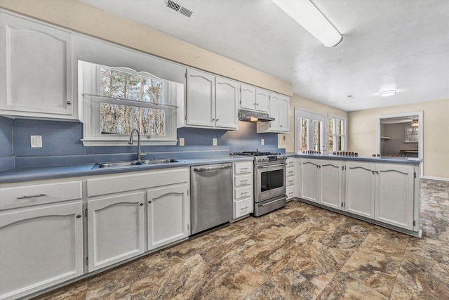 kitchen featuring visible vents, a sink, under cabinet range hood, appliances with stainless steel finishes, and a peninsula