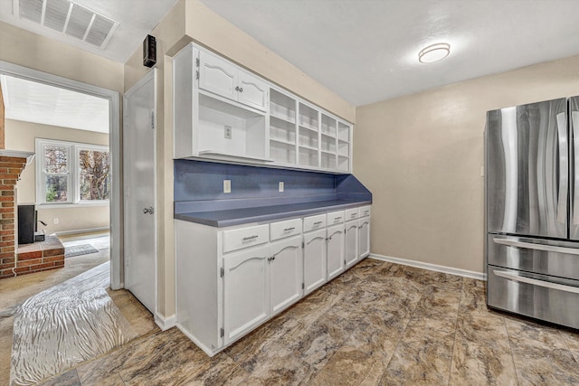 kitchen with visible vents, dark countertops, freestanding refrigerator, white cabinets, and baseboards