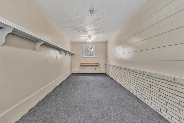 interior space featuring baseboards, ceiling fan, and dark carpet