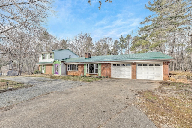 view of front of home featuring driveway, an attached garage, metal roof, brick siding, and a chimney