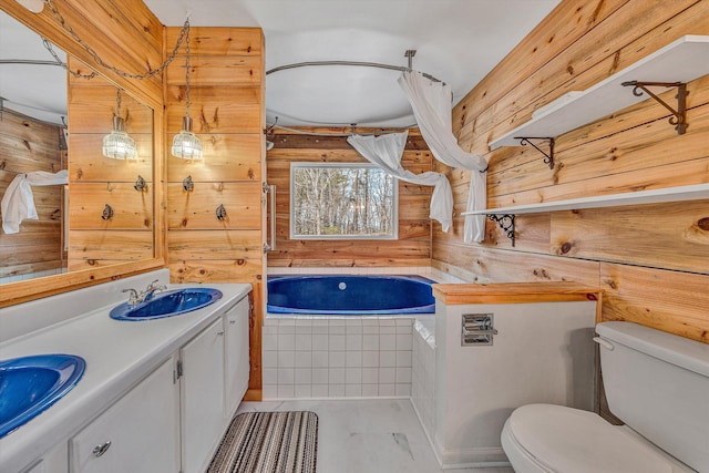 full bath featuring a relaxing tiled tub, toilet, wooden walls, and a sink