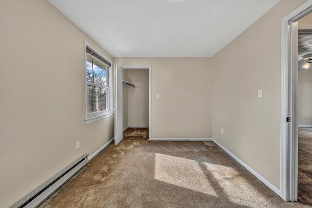 unfurnished bedroom featuring baseboards, a baseboard radiator, a spacious closet, a closet, and carpet flooring